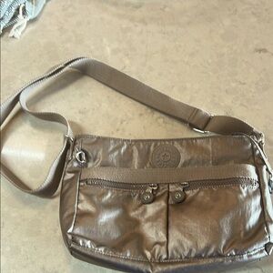 Metallic silver Crossbody Bag made by Kipling comes with monkey key ring